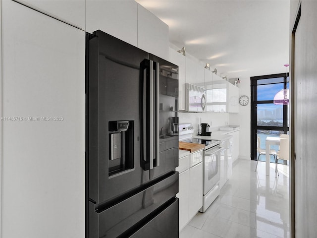 kitchen with white cabinetry, expansive windows, light tile patterned floors, and white appliances