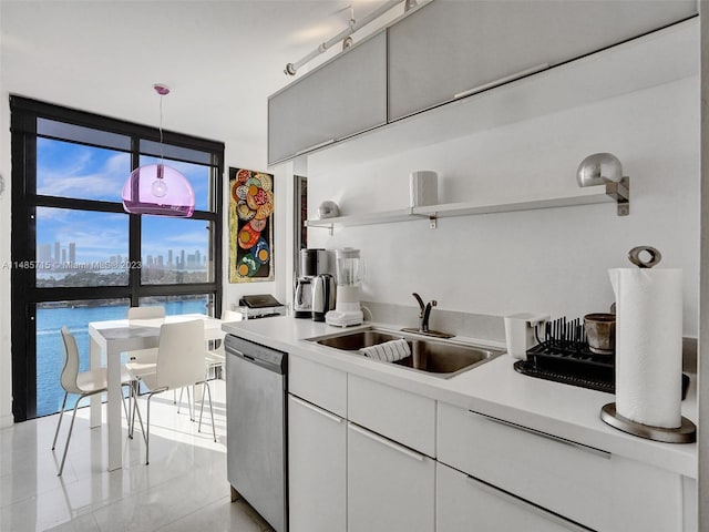 kitchen with sink, pendant lighting, light tile patterned floors, stainless steel dishwasher, and rail lighting