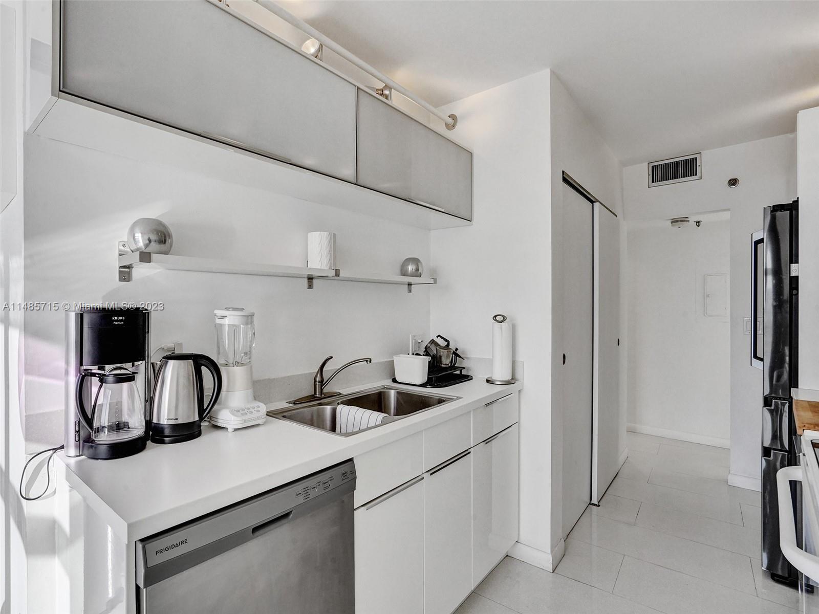 kitchen featuring light tile patterned flooring, dishwasher, white cabinetry, and sink