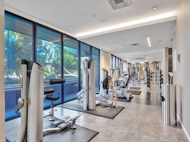 exercise room featuring light tile patterned floors and a wall of windows