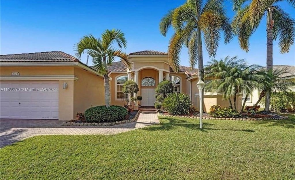 mediterranean / spanish-style house with a garage and a front lawn