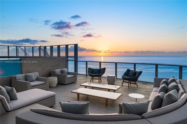 patio terrace at dusk featuring a balcony, a water view, and outdoor lounge area