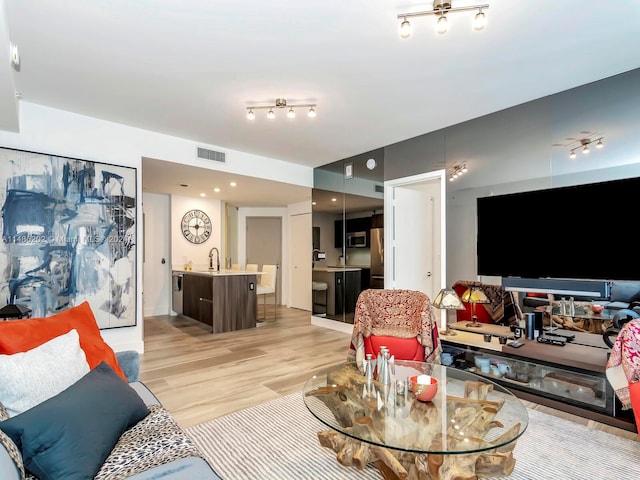 living room featuring sink and light hardwood / wood-style floors