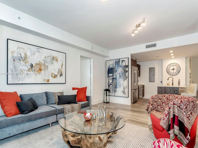 living room with sink, light hardwood / wood-style flooring, and electric panel