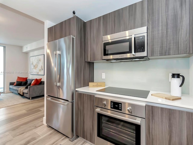 kitchen with light hardwood / wood-style floors and appliances with stainless steel finishes