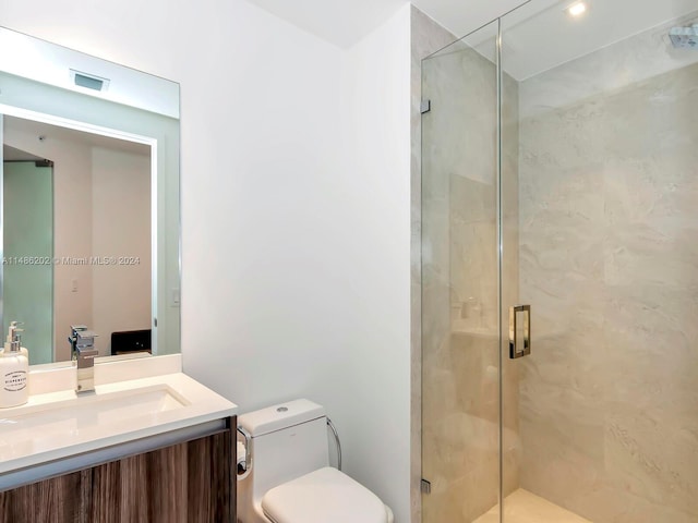 bathroom featuring vanity, a shower with shower door, and toilet