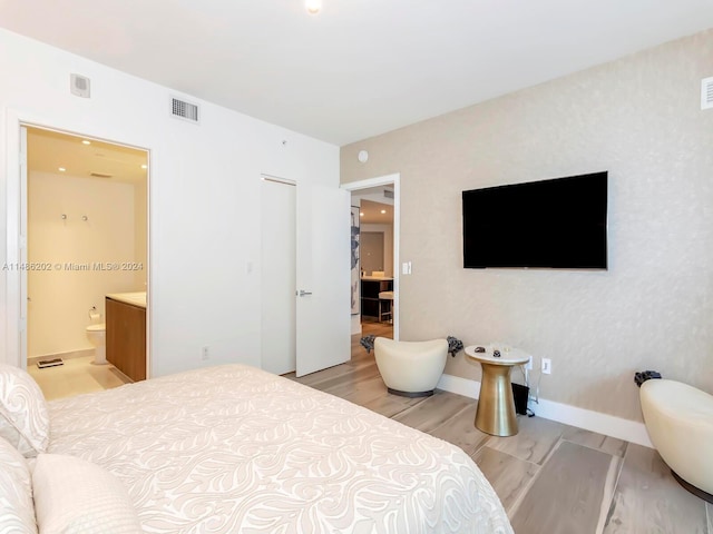 bedroom with light hardwood / wood-style flooring and connected bathroom