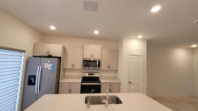 kitchen featuring white cabinetry, appliances with stainless steel finishes, light tile floors, and sink