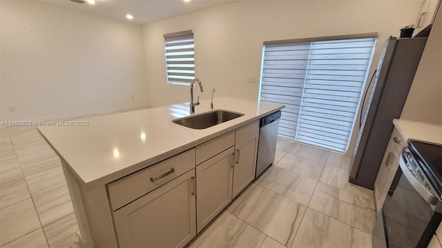 kitchen with a kitchen island with sink, sink, stainless steel appliances, light tile floors, and gray cabinets