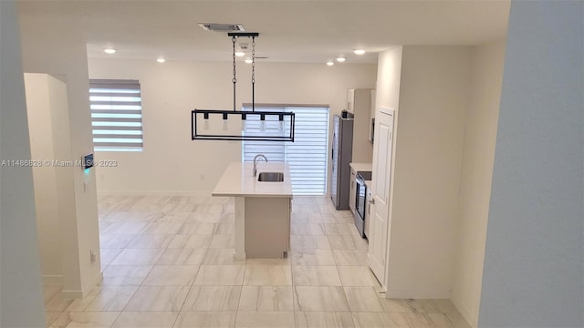 kitchen featuring a kitchen island with sink, white cabinets, sink, and light tile floors