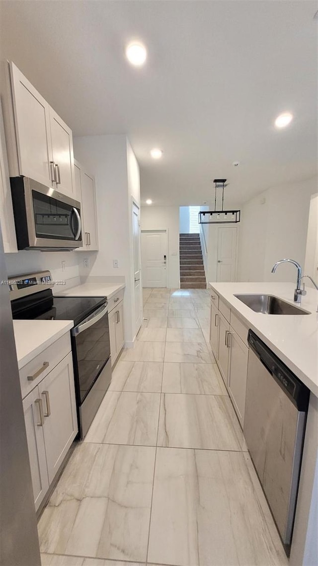 kitchen featuring pendant lighting, sink, light tile floors, white cabinets, and stainless steel appliances