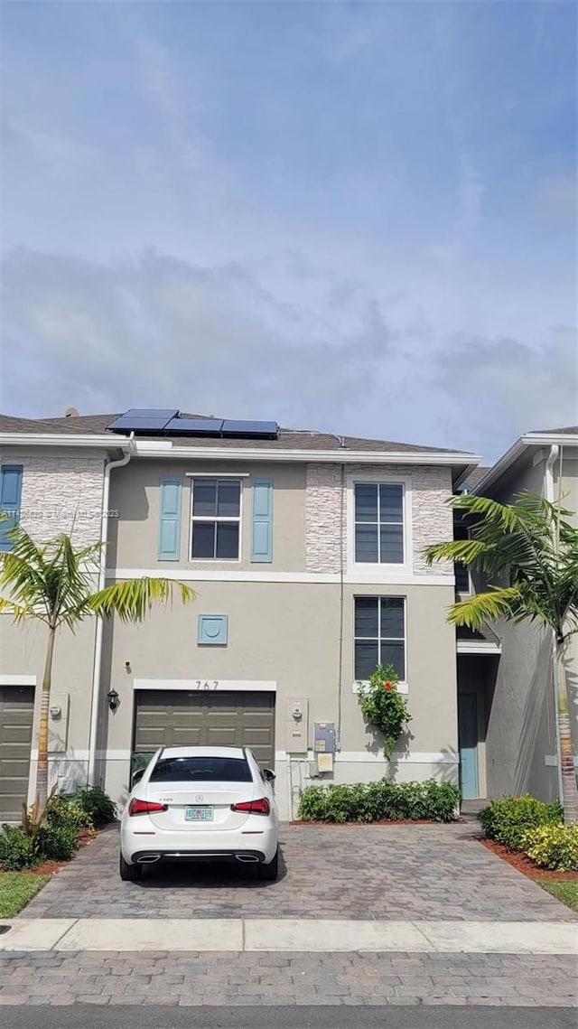 view of front of property featuring solar panels and a garage