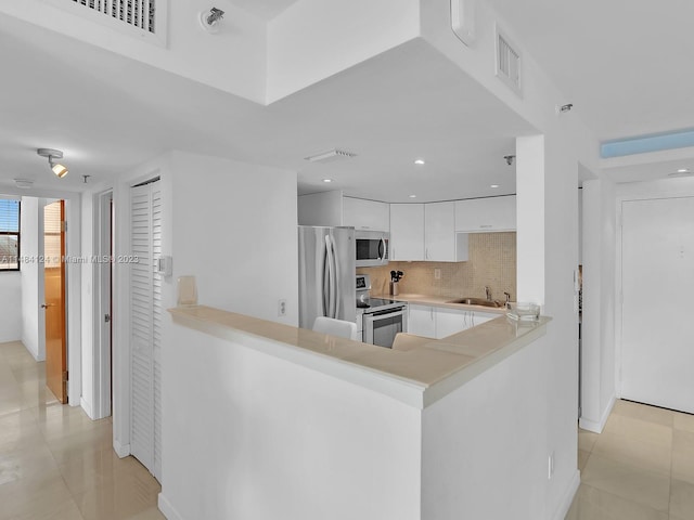 kitchen with white cabinetry, sink, stainless steel appliances, and kitchen peninsula