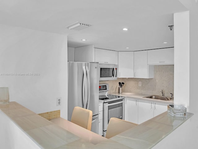 kitchen with white cabinetry, stainless steel appliances, sink, and backsplash