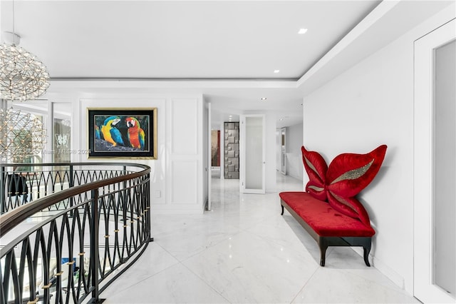 hall with a tray ceiling and light tile flooring