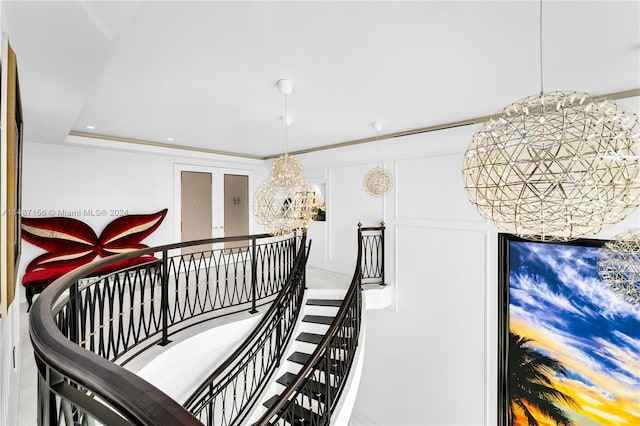 stairs featuring a tray ceiling and a chandelier