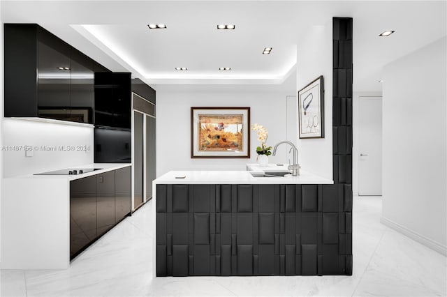 kitchen with a tray ceiling, light tile floors, and sink