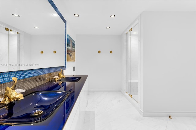 bathroom with double sink, a shower with shower door, backsplash, tile flooring, and large vanity