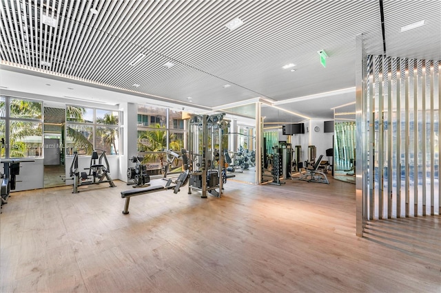 gym featuring an inviting chandelier and light hardwood / wood-style flooring