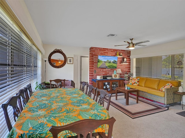 carpeted dining room with brick wall and ceiling fan