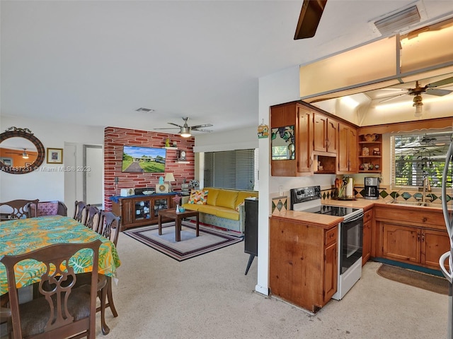 kitchen featuring white electric stove, ceiling fan, sink, and brick wall