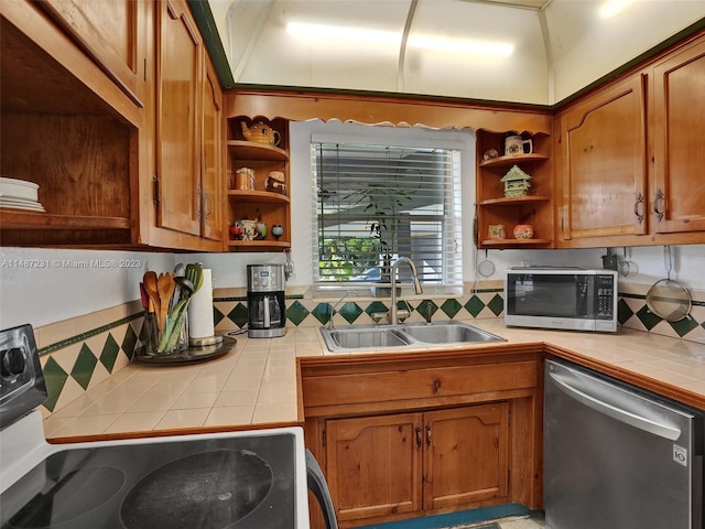 kitchen featuring stainless steel appliances, tasteful backsplash, lofted ceiling, tile countertops, and sink