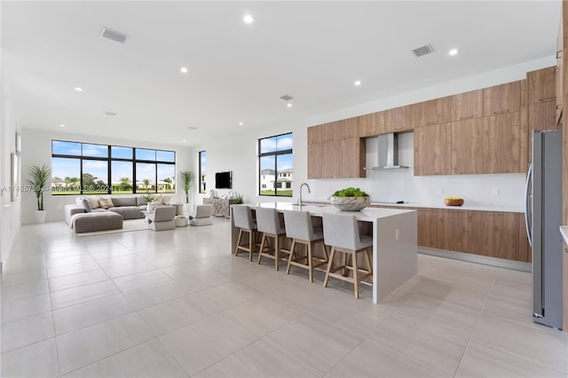 10455 SW 57th Ct, Cooper City, FL 33328 - kitchen featuring stainless steel fridge, sink, a kitchen breakfast bar, a center island with sink, and wall chimney exhaust hood