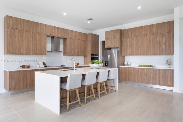 10455 SW 57th Ct, Cooper City, FL 33328 - kitchen with an island with sink, sink, a breakfast bar area, stainless steel appliances, and wall chimney range hood
