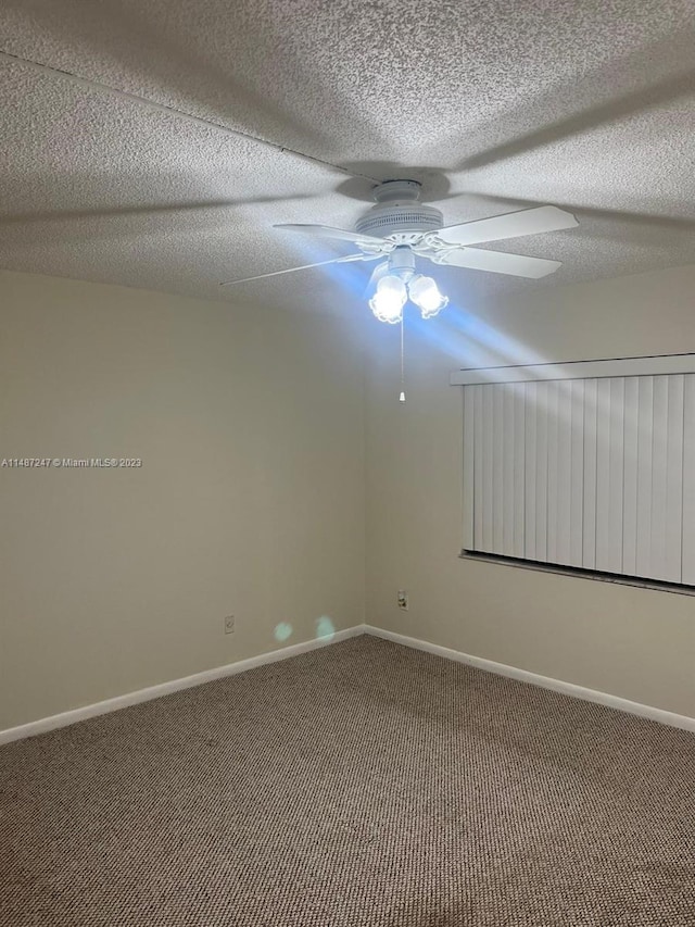 unfurnished room with a textured ceiling, dark colored carpet, and ceiling fan