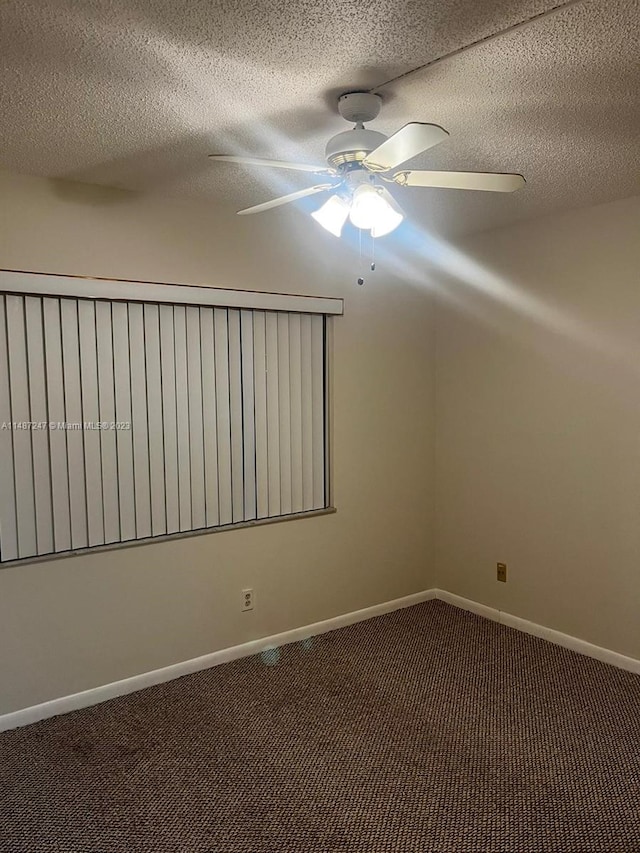 unfurnished room with a textured ceiling, dark carpet, and ceiling fan