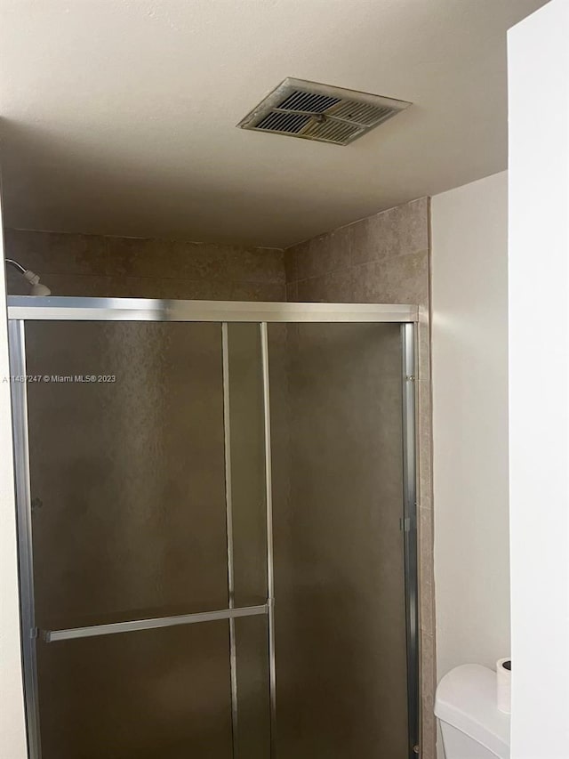 bathroom featuring toilet and a shower with shower door