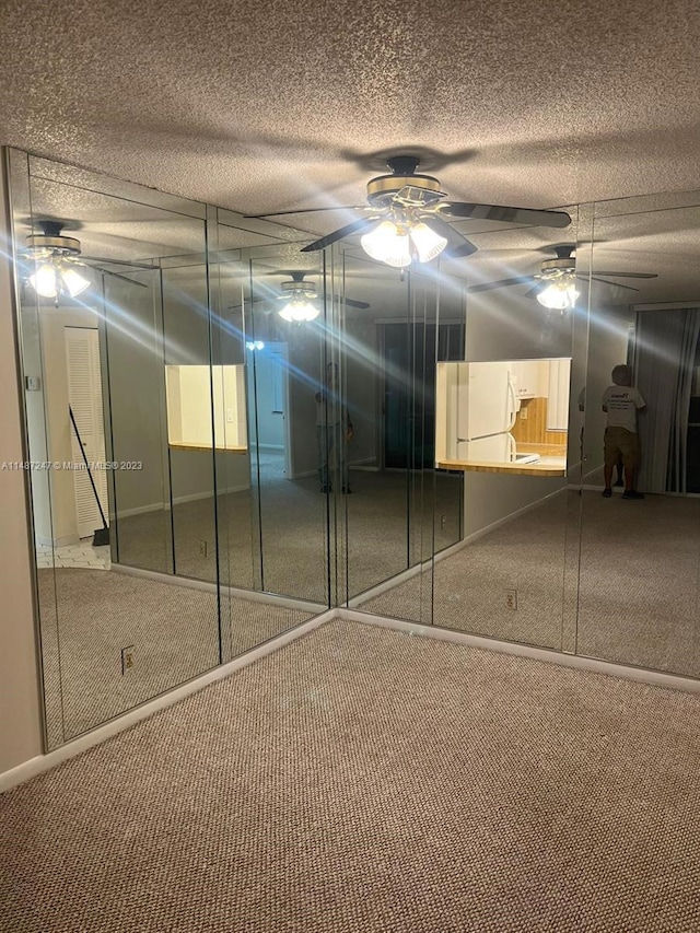 unfurnished bedroom with carpet floors, white fridge, ceiling fan, and a textured ceiling