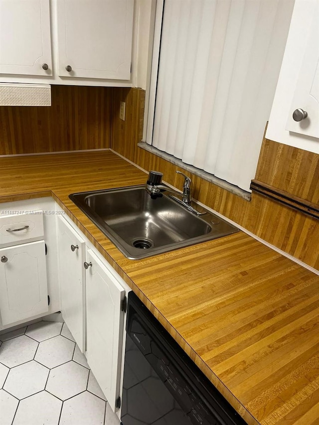 kitchen featuring light tile flooring, white cabinetry, dishwasher, and sink