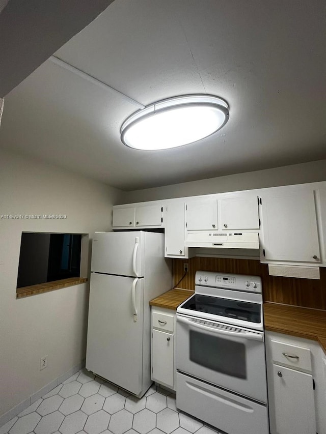 kitchen with white appliances, light tile flooring, and white cabinets