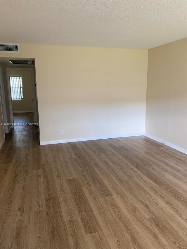 spare room featuring a textured ceiling and dark wood-type flooring