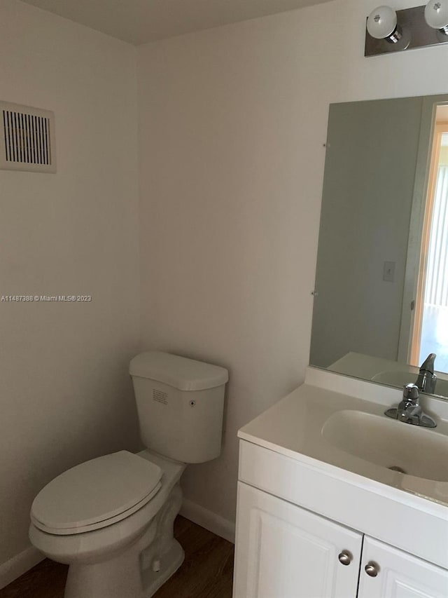 bathroom with toilet, vanity, and wood-type flooring