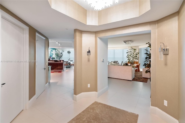 hallway with light tile flooring and a notable chandelier