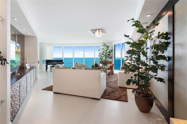 living room featuring plenty of natural light, a water view, a wall of windows, and light tile floors