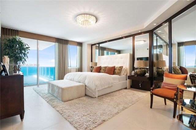 tiled bedroom featuring a chandelier, a wall of windows, and access to outside