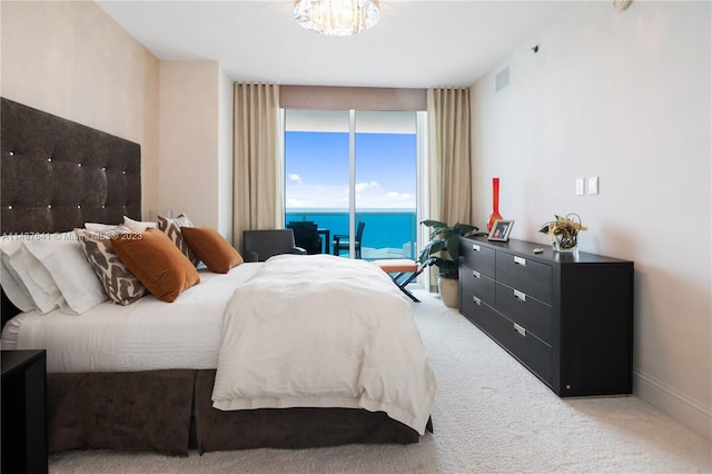 carpeted bedroom featuring an inviting chandelier, access to exterior, and a water view