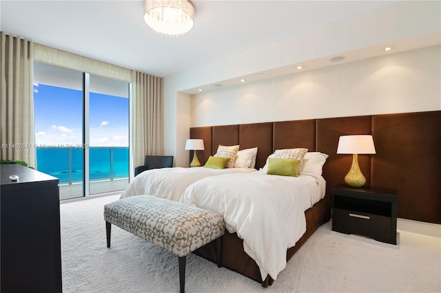 carpeted bedroom with a water view, access to outside, and an inviting chandelier