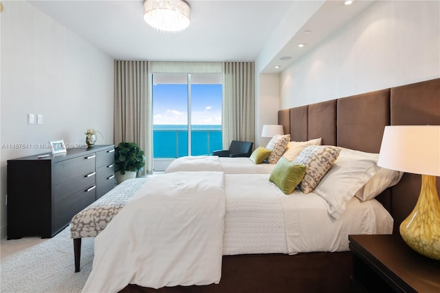 bedroom featuring light carpet, a water view, and access to exterior