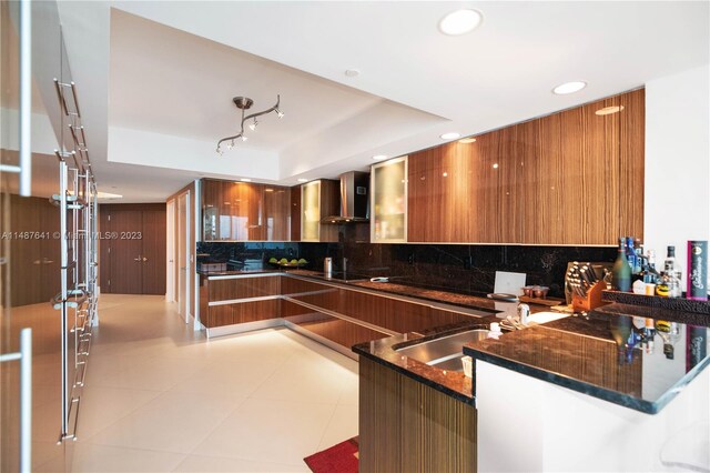 kitchen with backsplash, dark stone countertops, light tile floors, and wall chimney exhaust hood