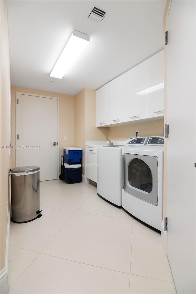 washroom with light tile floors, cabinets, and washing machine and clothes dryer