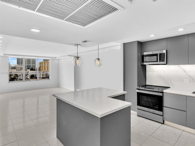 kitchen with appliances with stainless steel finishes, gray cabinets, a kitchen island, and hanging light fixtures