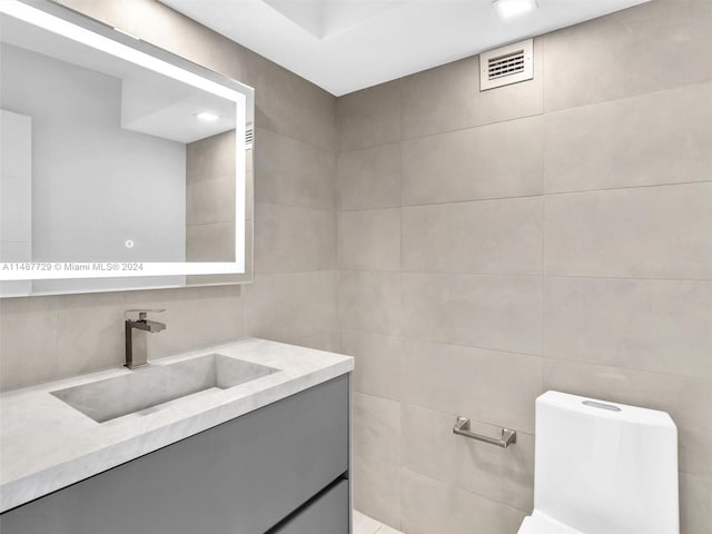 bathroom with tile walls, toilet, and vanity