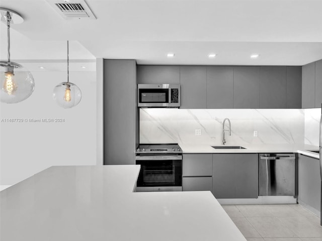 kitchen featuring appliances with stainless steel finishes, gray cabinets, light tile flooring, sink, and pendant lighting