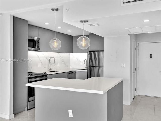 kitchen featuring hanging light fixtures, appliances with stainless steel finishes, sink, a kitchen island, and tasteful backsplash