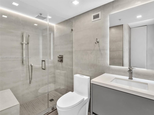 bathroom featuring vanity, an enclosed shower, toilet, and tile walls