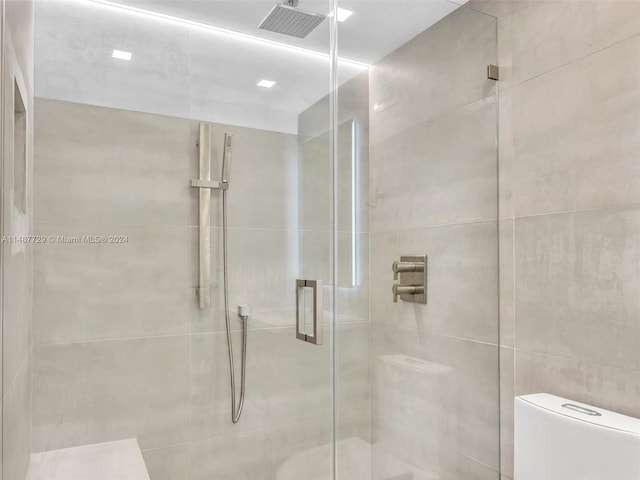 bathroom featuring walk in shower, toilet, and tile walls